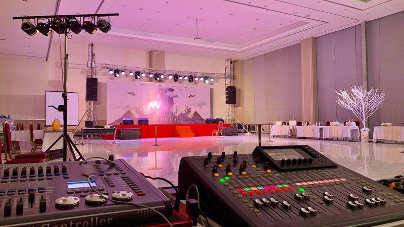 Bàn điều khiển âm thanh ánh sáng chuyên nghiệp được thiết lập trong hội trường tổ chức sự kiện với sân khấu và dàn đèn chiếu sáng hiện đại