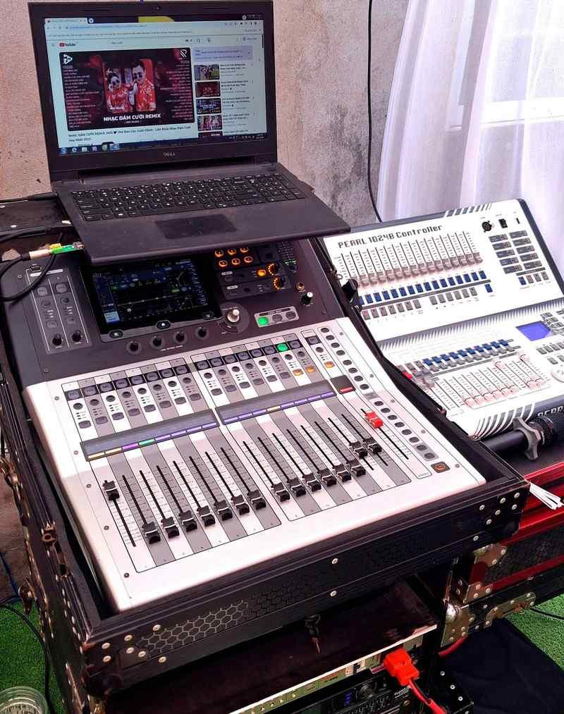 Bộ trộn âm thanh kỹ thuật số kết nối cùng laptop đang phát nhạc trên nền sự kiện