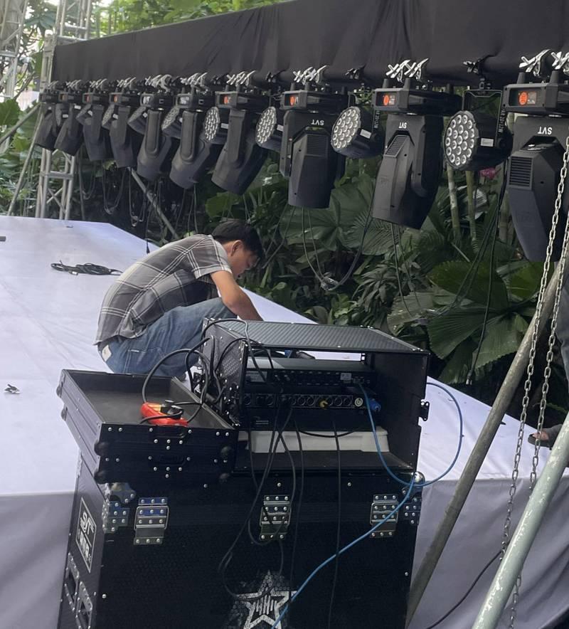 Kỹ thuật viên đang lắp đặt thiết bị âm thanh và ánh sáng cho sự kiện trên sân khấu ngoài trờ