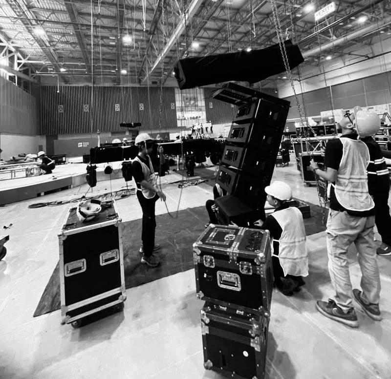 Nhóm kỹ thuật viên đang lắp đặt dàn âm thanh ánh sáng trong hội trường lớn chuẩn bị sự kiện