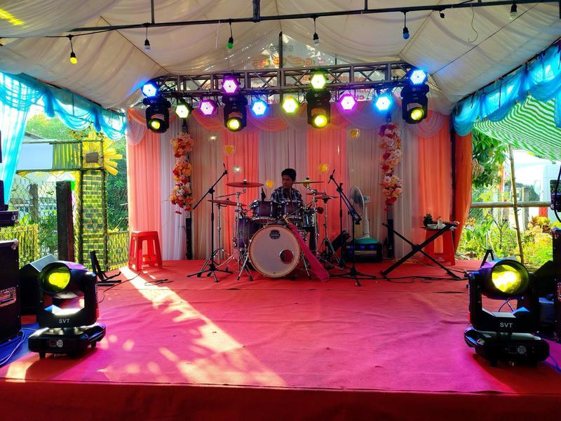 Sân khấu sự kiện ngoài trời với hệ thống âm thanh ánh sáng và người chơi trống đang biểu diễn