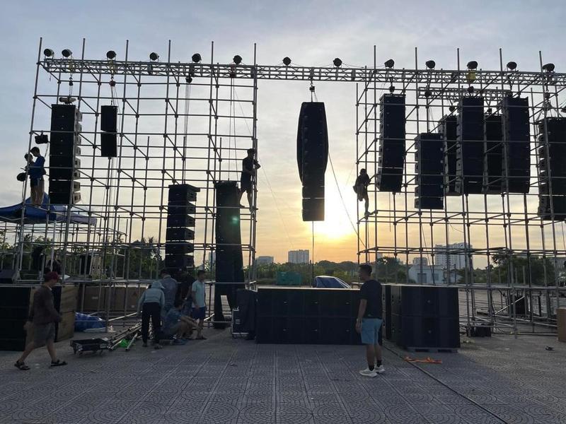 Nhóm kỹ thuật đang lắp đặt hệ thống âm thanh ánh sáng sự kiện ngoài trời vào lúc hoàng hôn