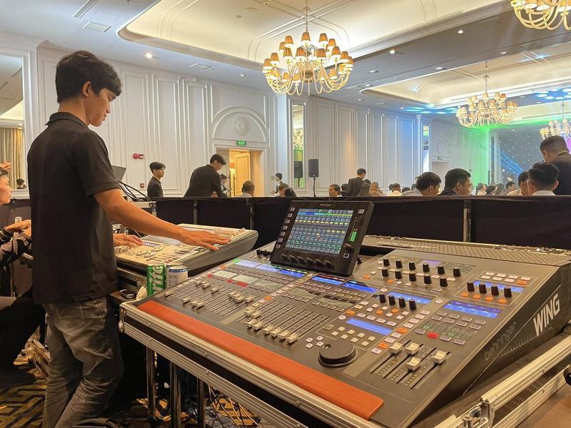 Kỹ thuật viên điều khiển bàn mixer âm thanh tại sự kiện trong hội trường sang trọng