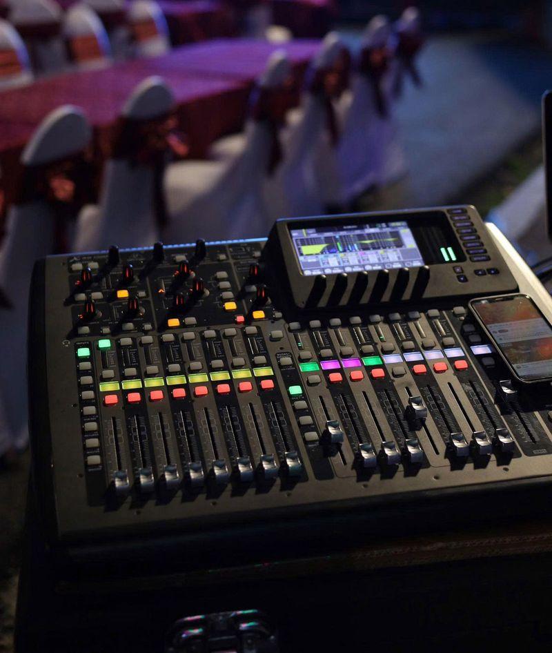 Bàn trộn âm thanh chuyên nghiệp với các nút điều chỉnh và màn hình hiển thị trong không gian sự kiện