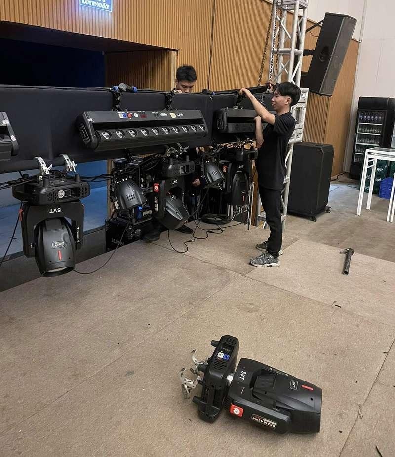 Kỹ thuật viên đang lắp đặt thiết bị ánh sáng sự kiện chuyên nghiệp trong không gian hội trường