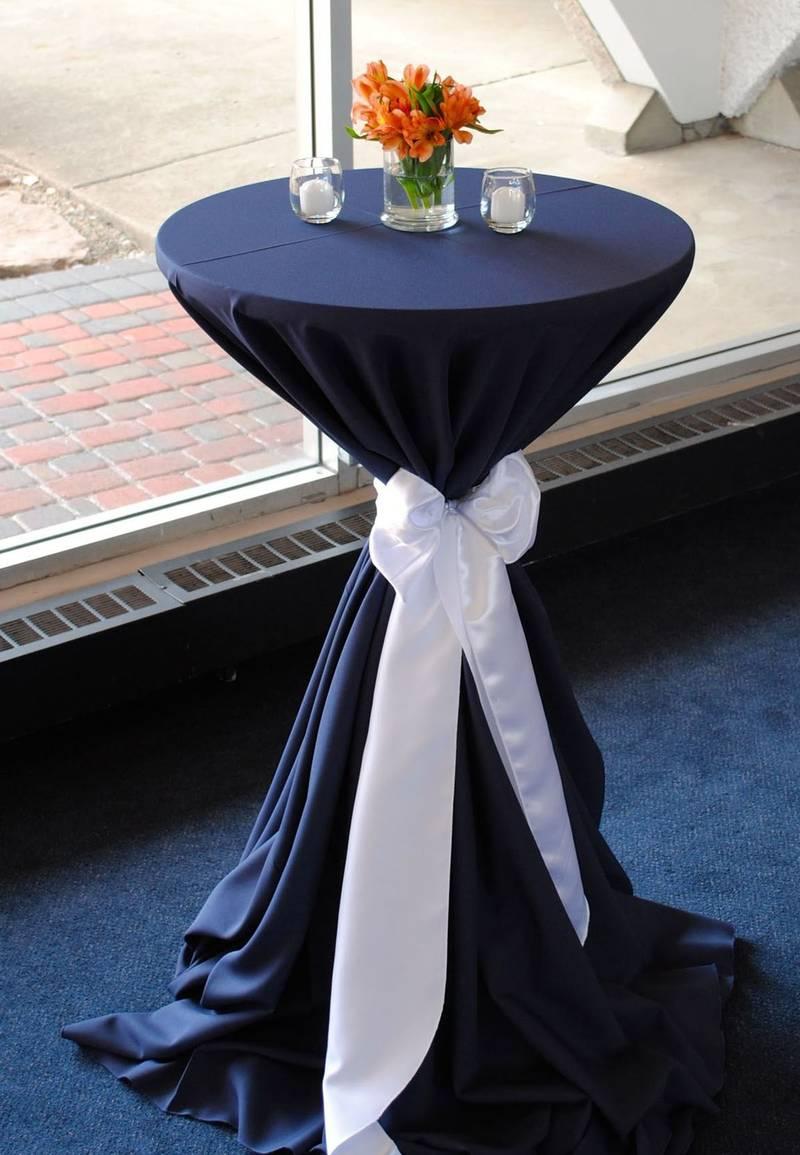 Cho thuê bàn ghế sự kiện với bàn cao bọc vải xanh đen thắt nơ trắng sang trọng tại TP.HCM.