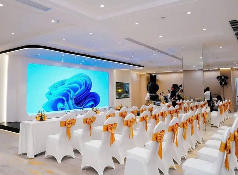 Cho thuê bàn ghế sự kiện giá rẻ tại TP.HCM với ghế trắng đính nơ cam trong phòng hội nghị hiện đại.