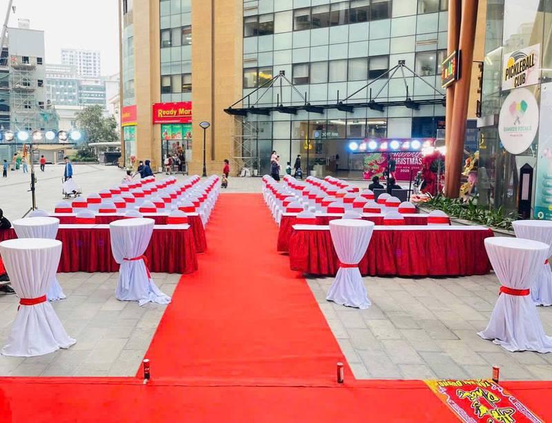 Cho thuê bàn ghế sự kiện giá rẻ tại TP.HCM với bàn ghế được bọc khăn trắng và nơ đỏ chuẩn bị cho sự kiện ngoài trời.