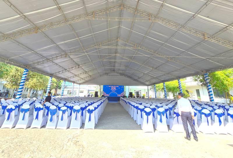 Cho thuê bàn ghế sự kiện giá rẻ tại TP.HCM với dàn ghế trắng nơ xanh được sắp xếp ngăn nắp dưới mái che rộng.