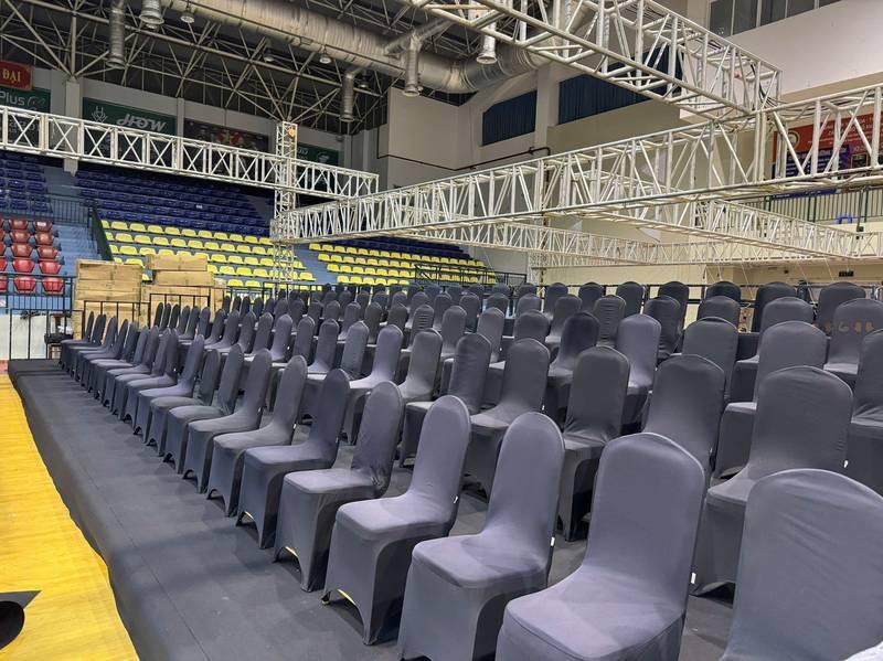 Cho thuê bàn ghế sự kiện giá rẻ tại TP.HCM với dãy ghế bọc vải đen sắp xếp trong hội trường.