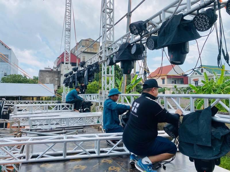 ALT ảnh: Nhân viên lắp đặt cho thuê đèn sự kiện với đèn sân khấu par led và moving beam giá rẻ trên khung sắt ngoài trời.