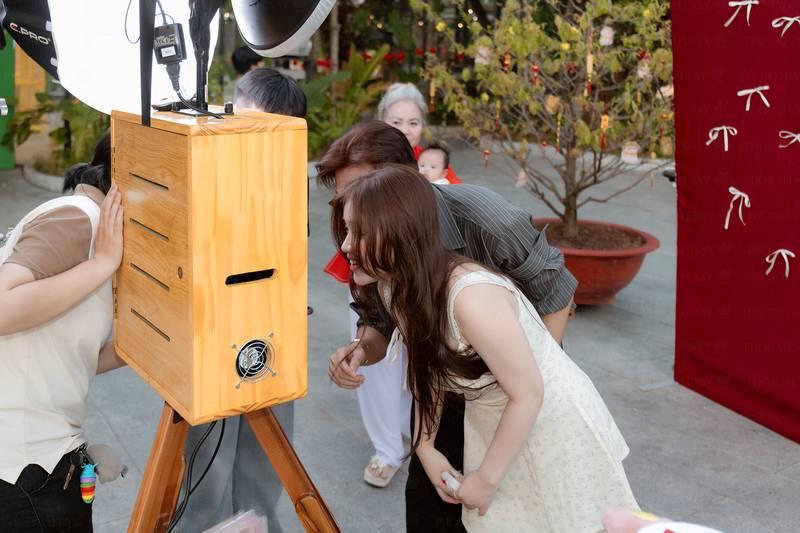 Cho thuê photobooth sự kiện trọn gói giá rẻ HCM với máy chụp ảnh photobooth gỗ và khách đang chụp hình.