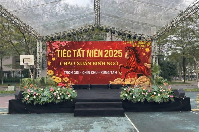 ALT: Sân khấu sự kiện trọn gói cho thuê sân khấu sự kiện giá rẻ HCM tổ chức tiệc tất niên 2025 với backdrop đỏ và trang trí hoa.