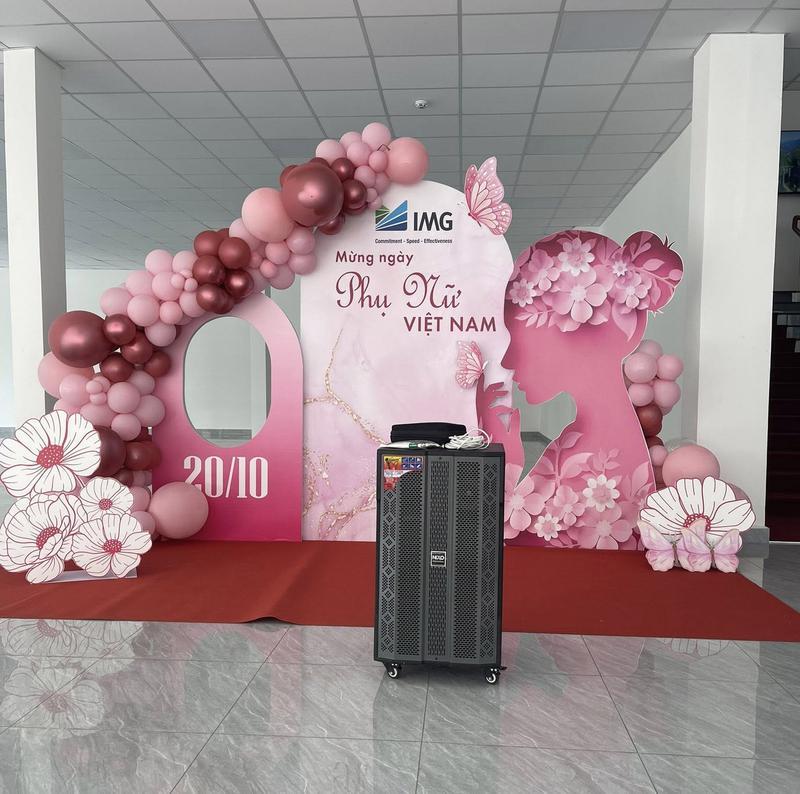 Loa kẹo kéo được đặt trước backdrop trang trí ngày Phụ Nữ Việt Nam với bóng bay hồng, thể hiện dịch vụ cho thuê loa kẹo kéo phục vụ sự kiện