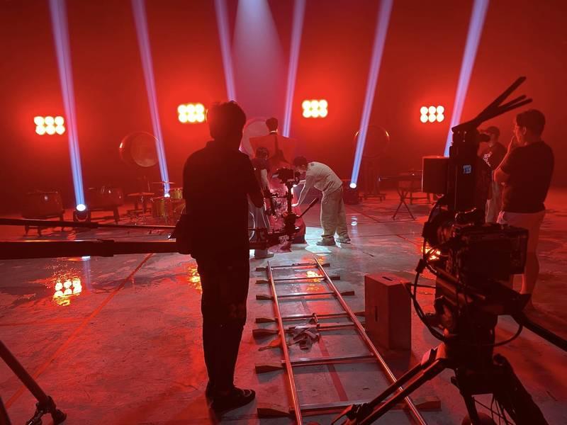 Ekip chuyên nghiệp đang thực hiện dịch vụ quay phim chụp ảnh sự kiện trọn gói với thiết bị hiện đại trong không gian ánh sáng đỏ.