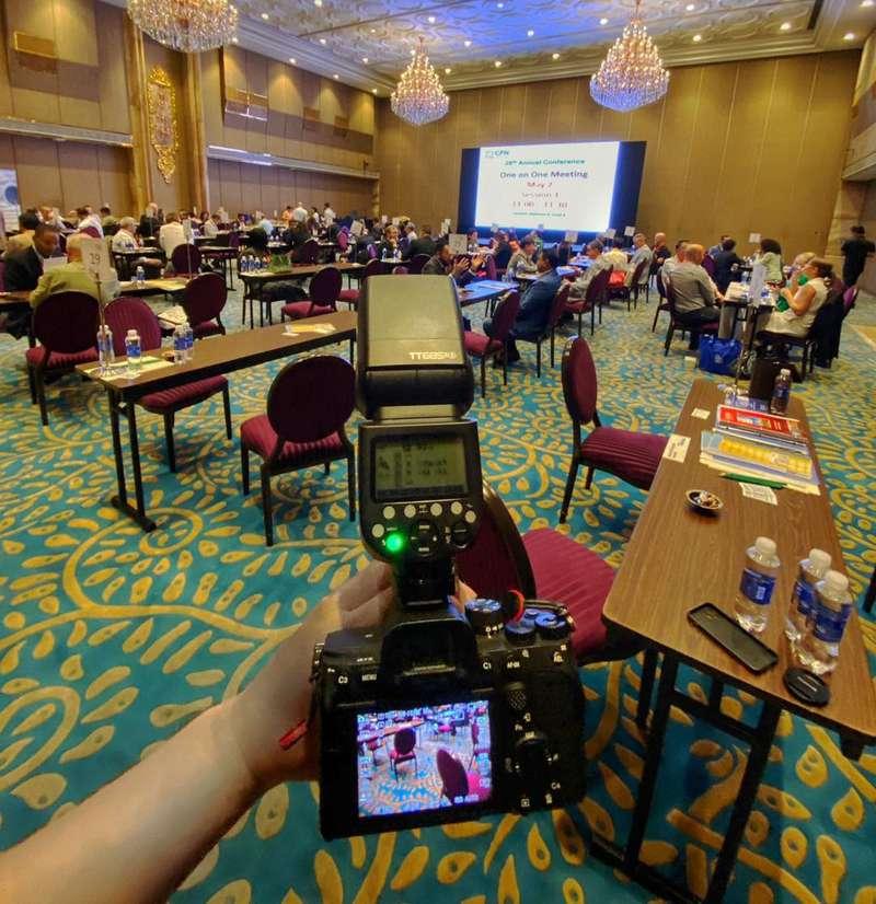 Ảnh một nhiếp ảnh gia sử dụng dịch vụ quay phim chụp ảnh sự kiện trọn gói với ekip chuyên nghiệp tại hội nghị trong phòng hội thảo sang trọng.