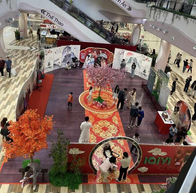 Không gian sự kiện tổ chức activation tại trung tâm thương mại với trang trí cây hoa và backdrop nổi bật, dịch vụ tổ chức activation trọn gói - agency activation uy tín.