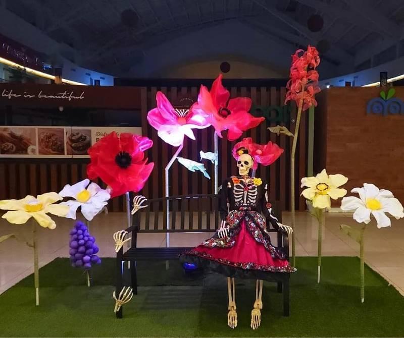 ALT ảnh: Trang trí ma quái với bộ xương mặc váy bên hoa lớn trong tổ chức sự kiện Halloween trọn gói HCM.