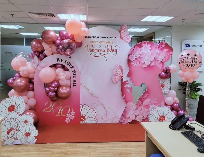 Backdrop 8/3 và 20/10 trang trí tiểu cảnh ngày phụ nữ công ty với bóng bay và hoa văn hồng nghệ thuật.