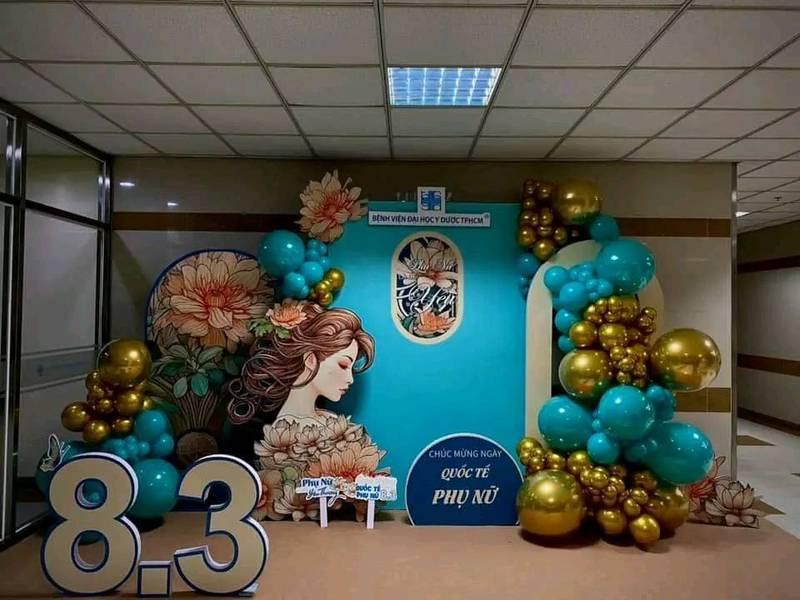 ALT: Tiểu cảnh trang trí ngày phụ nữ công ty với backdrop 8/3 và bóng bay vàng xanh tại văn phòng.