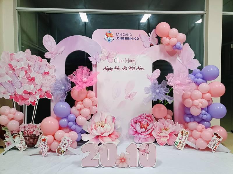 Tiểu cảnh trang trí ngày phụ nữ công ty với backdrop 20/10, bóng bay và hoa hồng mềm mại tạo không gian văn phòng ấm áp.