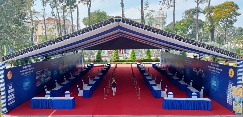 ALT: Trang trí sân khấu sự kiện với thiết kế và thi công trọn gói HCM tại hội trường ngoài trời có mái che và bàn ghế xanh dương.