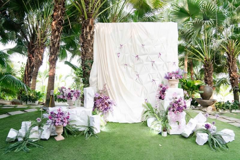 Trang trí sân khấu sự kiện ngoài trời với nền trắng và hoa tím, dịch vụ thiết kế và thi công trọn gói tại HCM.